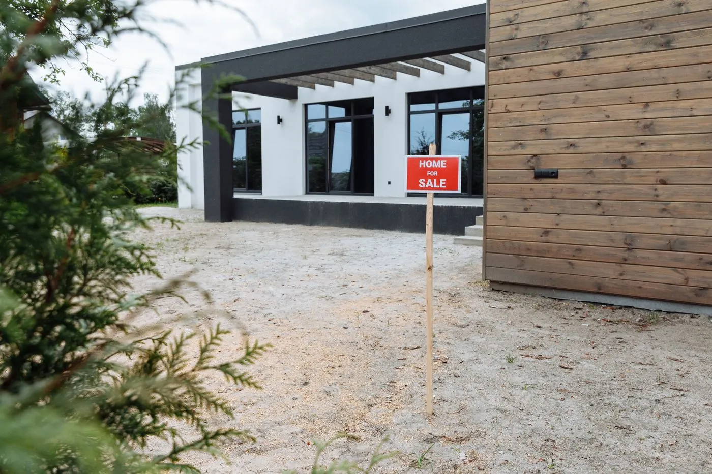moderní dům s cedulí Home for Sale u vchodu