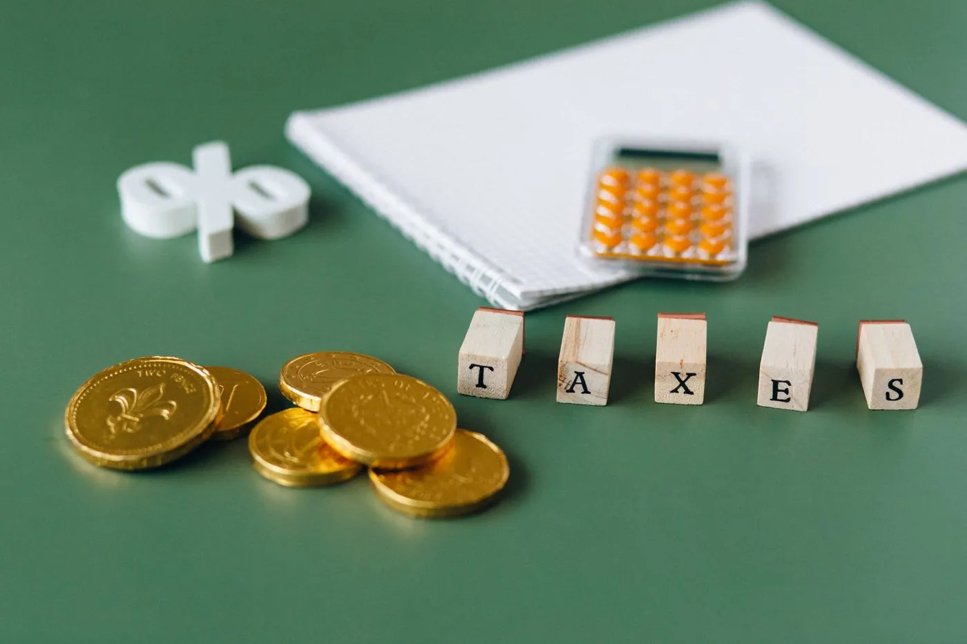 Mince a dřevěné kostky s nápisem taxes na zeleném pozadí