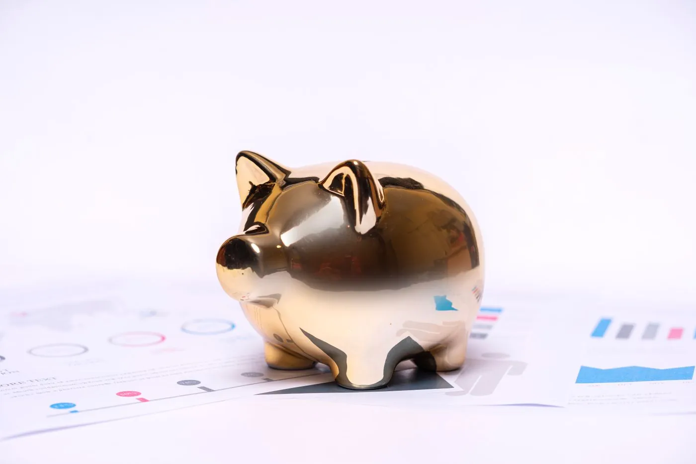 Zlatá pokladnička stojící na finančních dokumentech