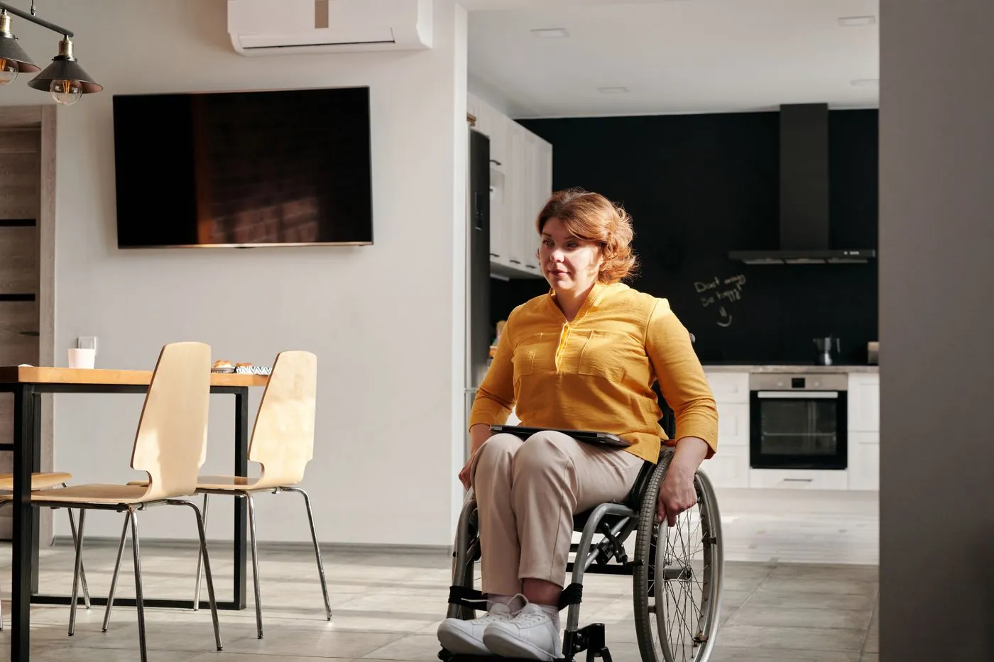 Žena na invalidním vozíku v přizpůsobené domácí kuchyni