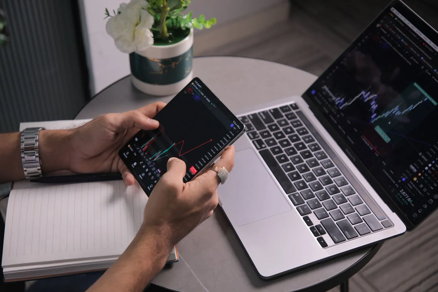 Muž sleduje burzovní trendy na notebooku a mobilu