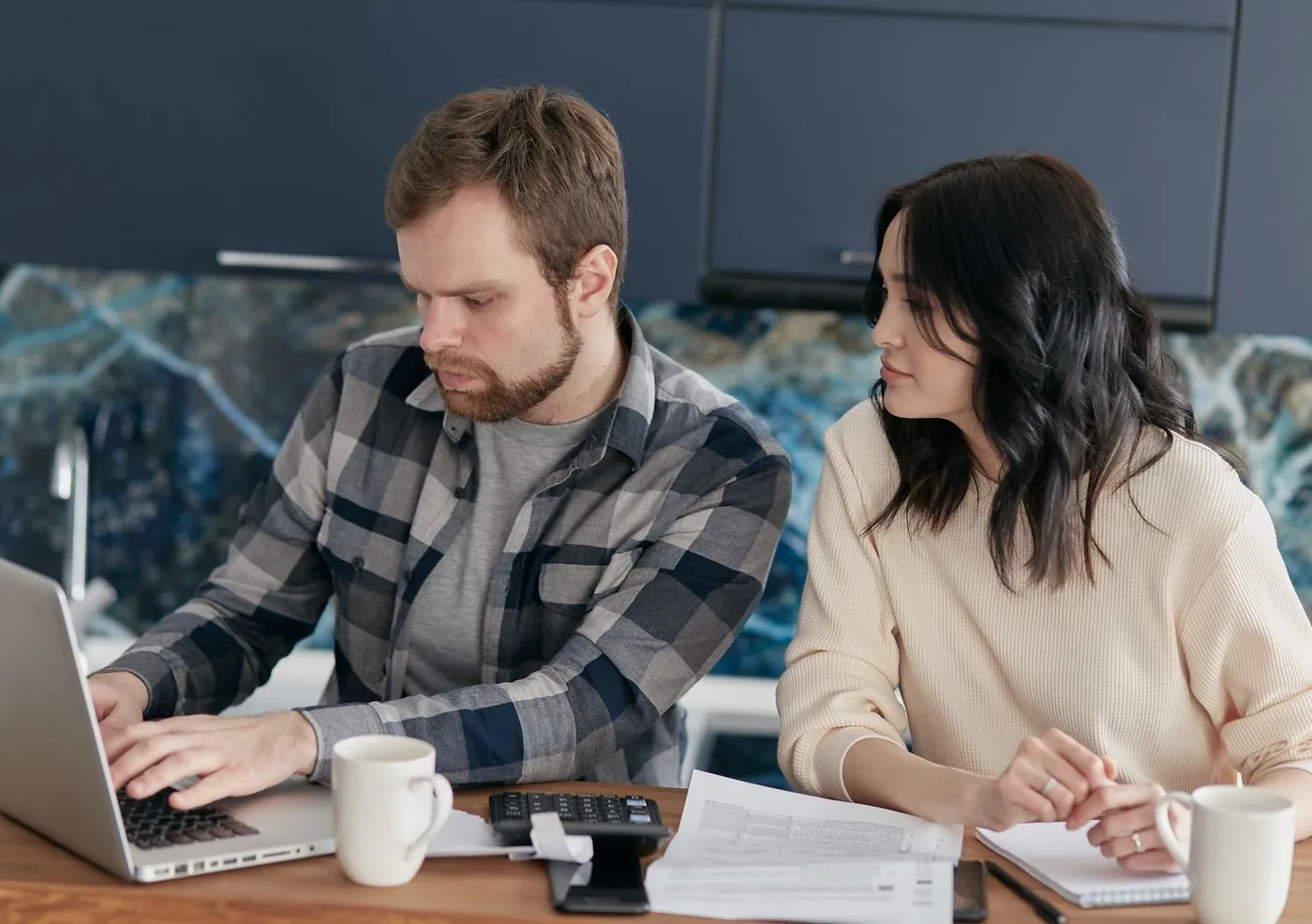 Pár doma společně řeší finance s notebookem a papíry