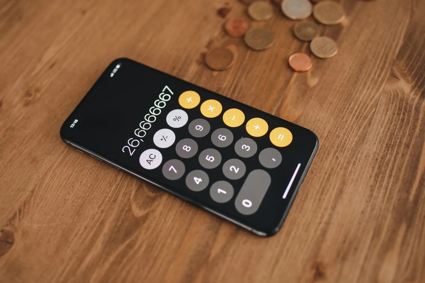 Kalkulačka na displeji telefonu mezi mincemi na stole