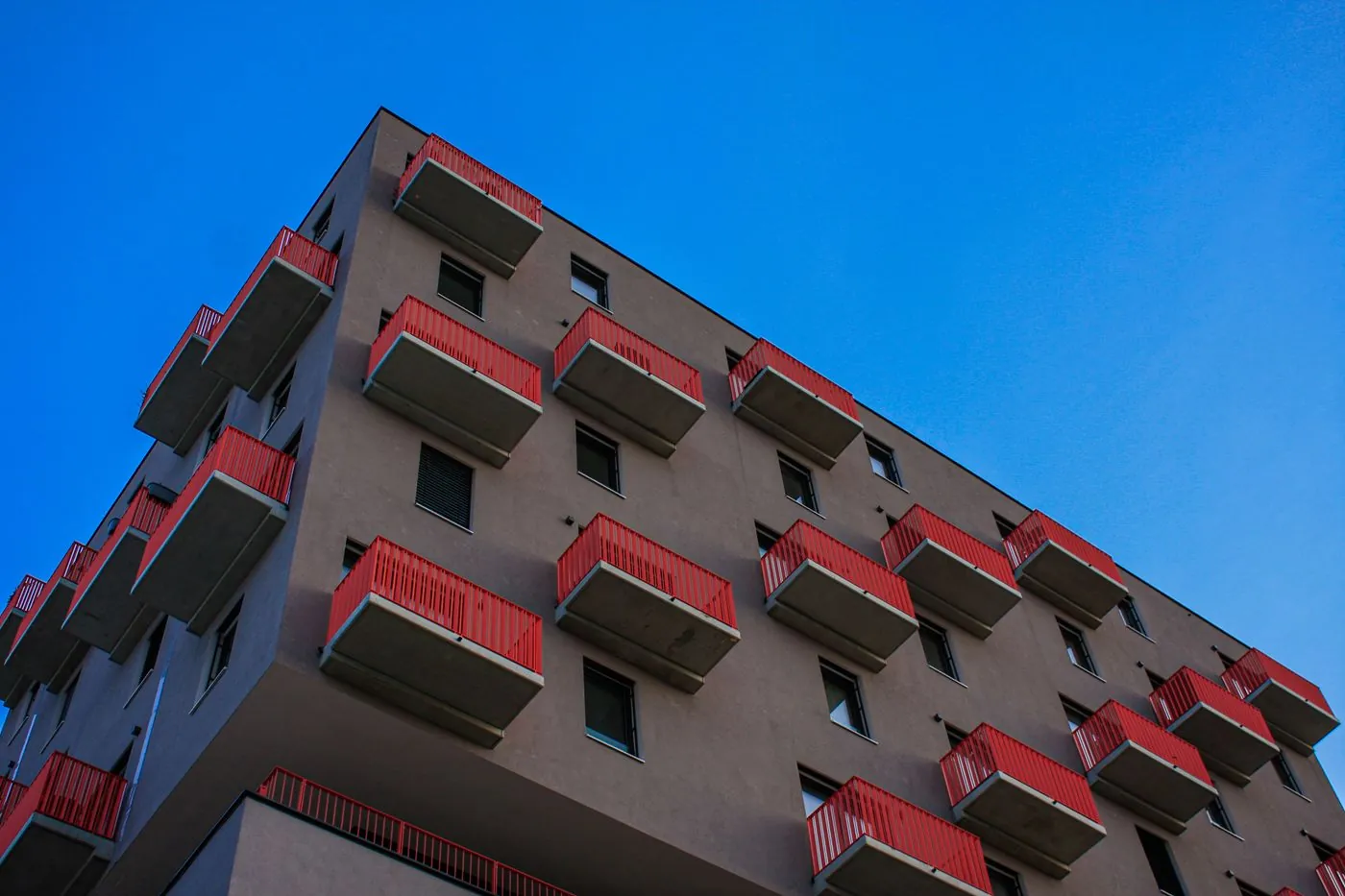 bytový dům s červenými balkony na modré obloze
