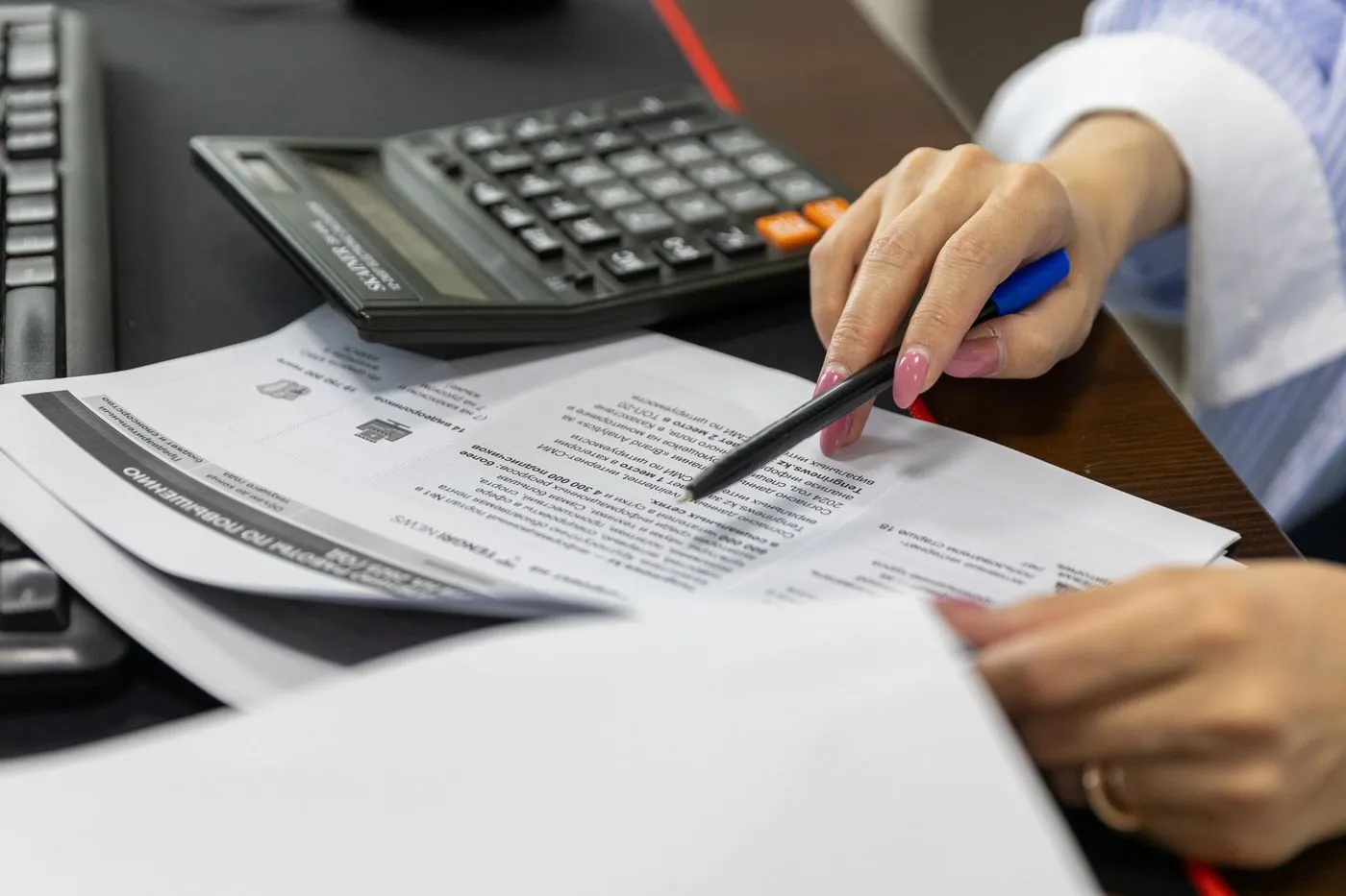 ruka kontroluje finanční dokumenty s kalkulačkou