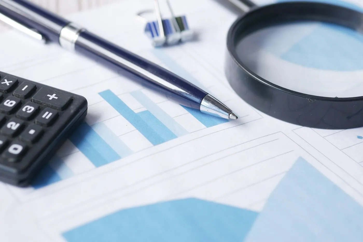 kalkulačka, pero a lupa na finančních dokumentech