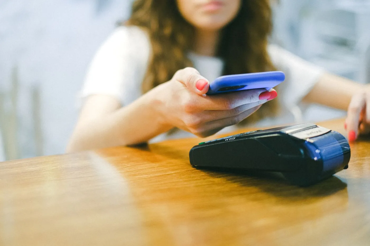 Žena platí telefonem přiložením k platebnímu terminálu