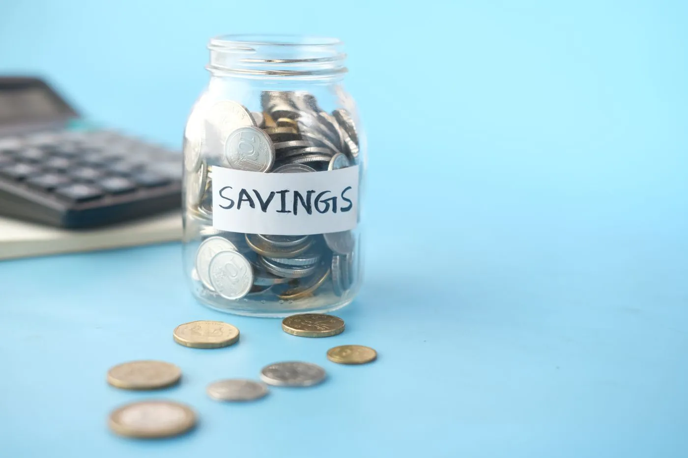 Sklenice s mincemi a nápisem savings vedle kalkulačky