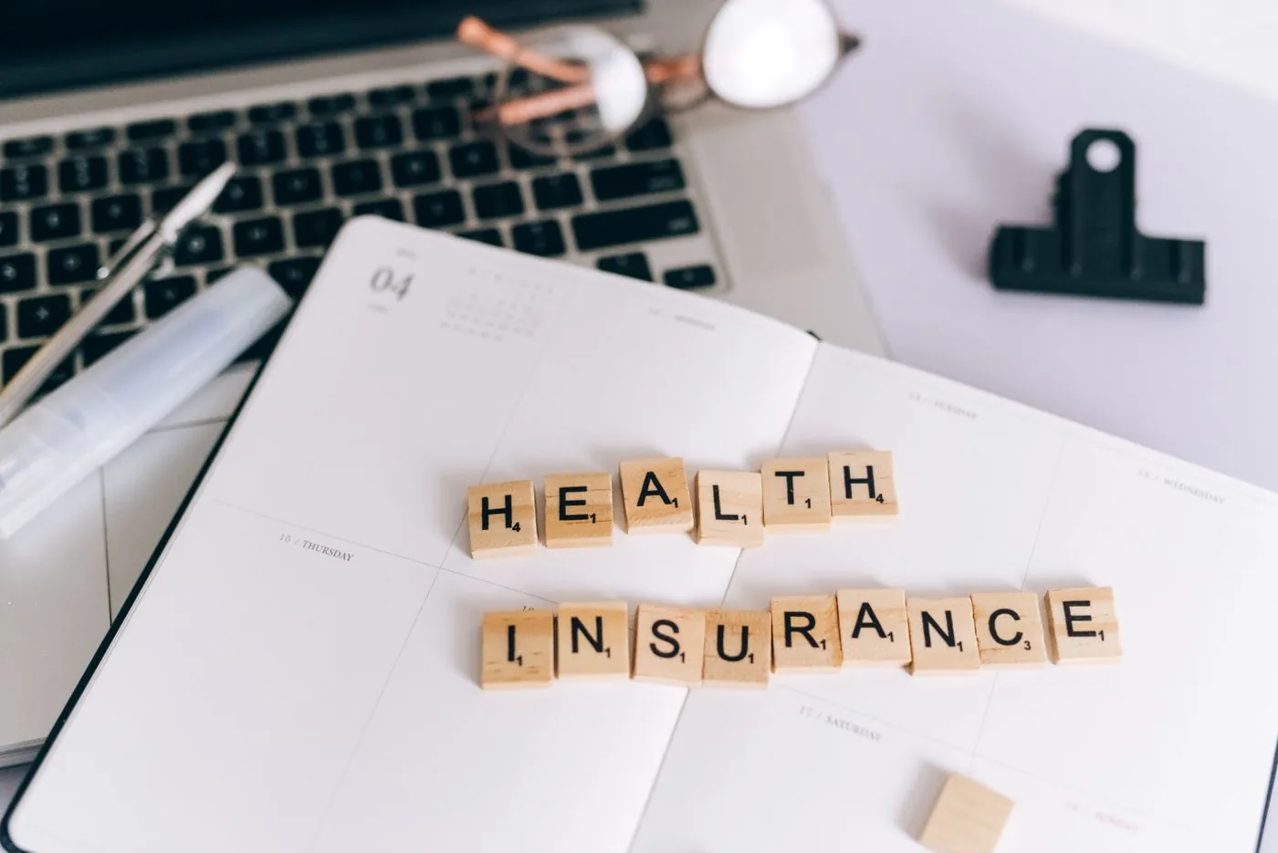 Dřevěné kostky s nápisem Health Insurance vedle notebooku